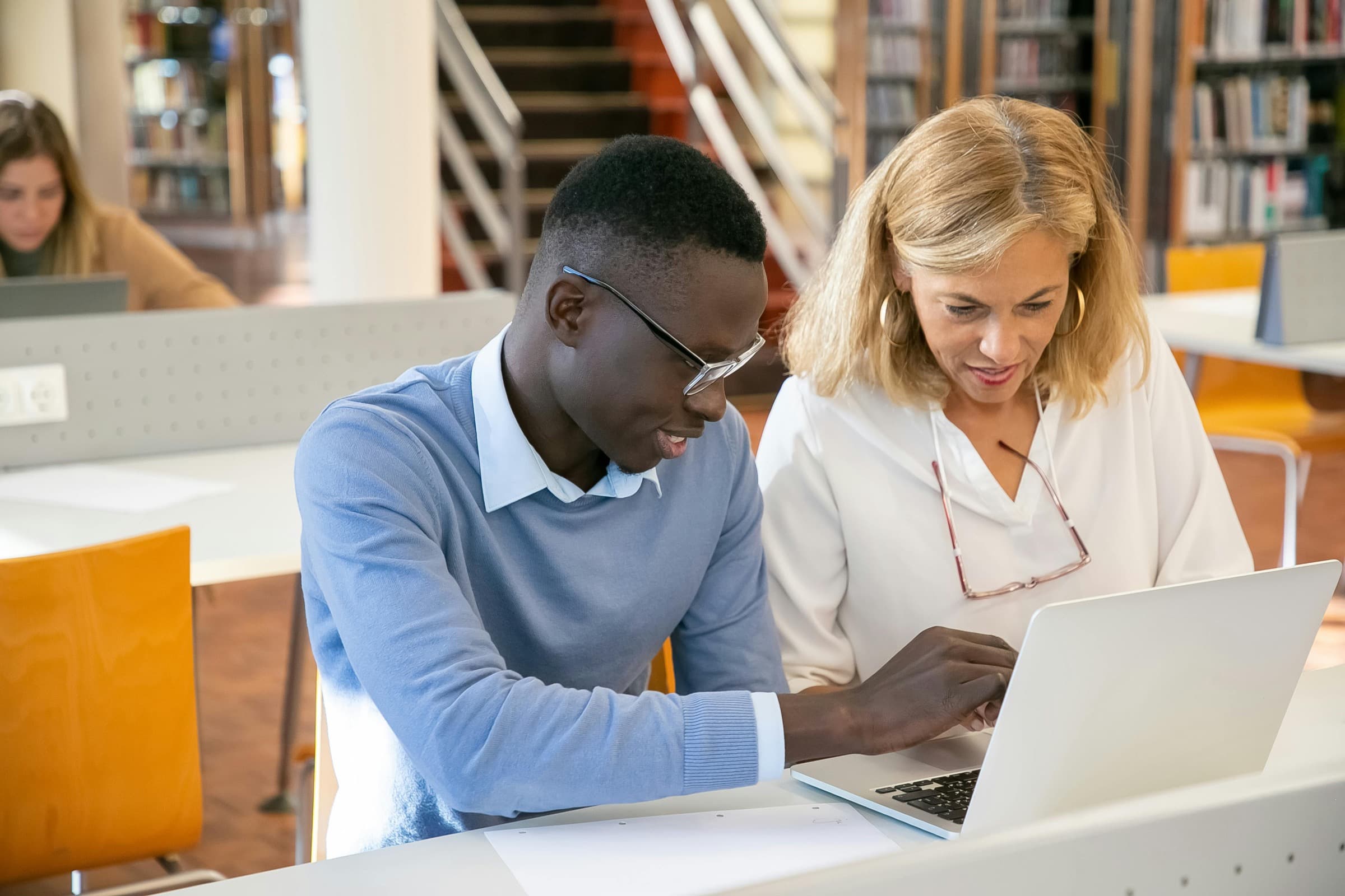 A college adviser working one-on-one with a student on a laptop